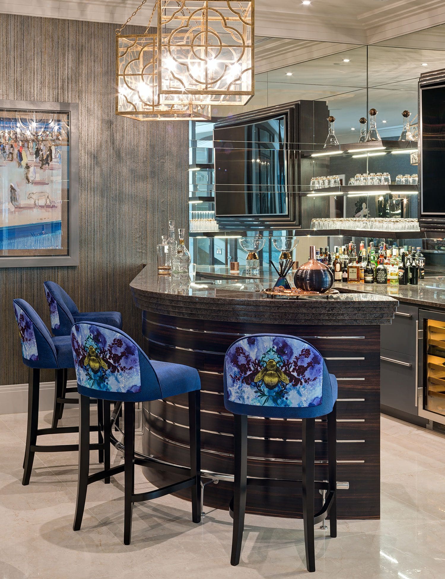 A home bar with image optimization features a curved granite countertop, blue patterned barstools, and a mirrored backsplash. Shelves are stocked with glassware and bottles, perfectly aligning with SEO keywords. A geometric chandelier hangs elegantly above.